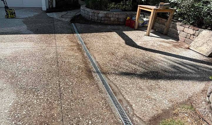A trench drain installed across a concrete driveway to correct water pooling